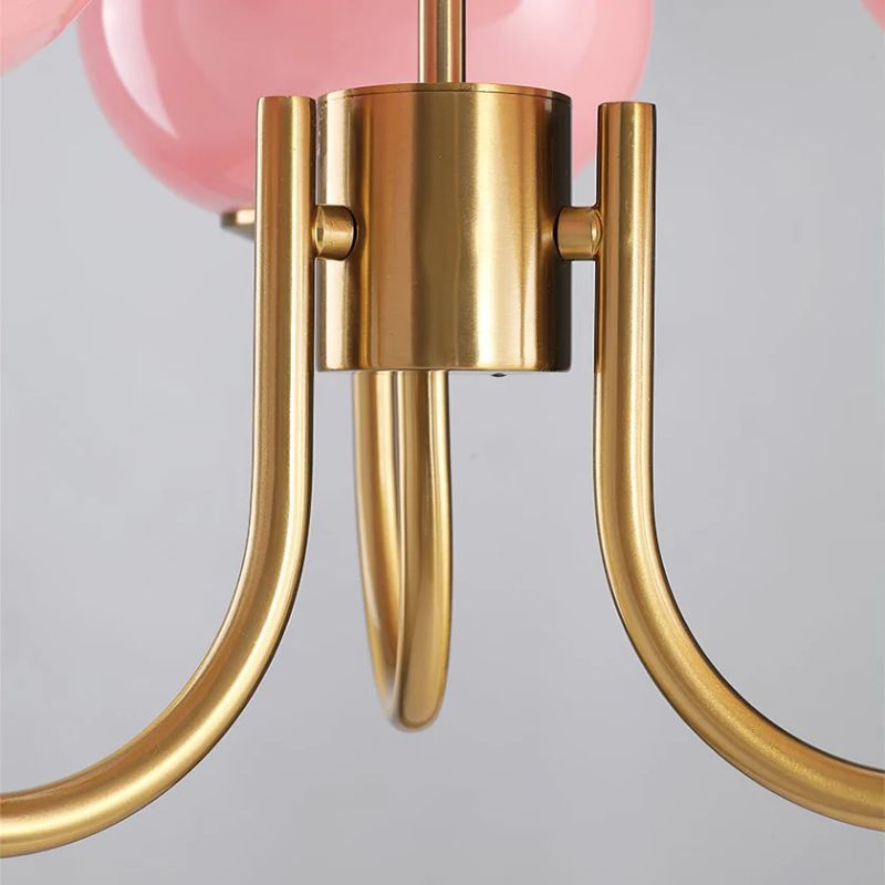 Close-up of a gold chandelier with pink glass shades on a gray background